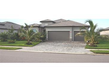 Beautiful single-story home featuring a well-maintained lawn, tropical landscaping, and a three-car garage with a paver driveway at 4957 Seafoam Trl, Bradenton, FL 34211