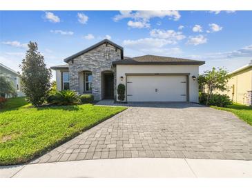 Charming single-story home featuring a stone facade, manicured lawn, and a paved driveway leading to a two-car garage at 6211 Sea Air Dr, Apollo Beach, FL 33572