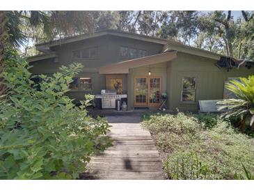 A charming exterior view showcases a unique home design with a wood pathway and lush landscaping at 6924 Valrie Ln, Riverview, FL 33569
