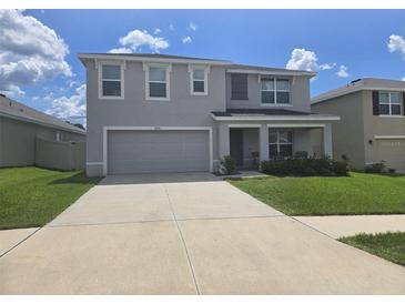Charming two-story home features a two-car garage, well-maintained lawn, and inviting front porch at 7575 Sail Clover Ln, Zephyrhills, FL 33540