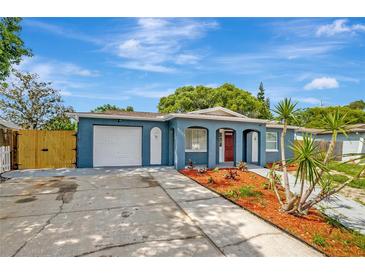 Charming blue single-story home with a well-manicured lawn, complemented by a red front door and attached garage at 8033 Norwich Dr, Port Richey, FL 34668