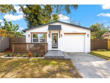 Charming home with a deck, white exterior, modern front door, and a one car garage at 403 E North St, Tampa, FL 33604
