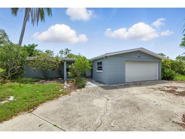 Single-story home with a gray exterior, an attached garage and a large concrete driveway at 4101 Shore Acres Ne Blvd, St Petersburg, FL 33703