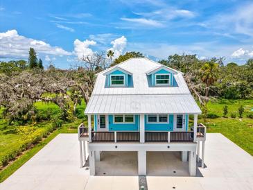 Charming coastal-style home with a metal roof, eye-catching blue accents and a raised design with covered parking at 6679 Wander Ln, New Port Richey, FL 34652