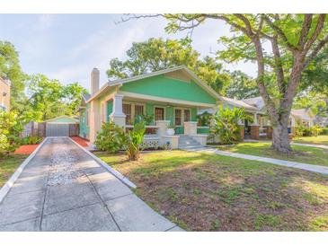 Charming green bungalow with a welcoming front porch and a well-manicured lawn and a detached garage at 1202 E Mohawk Ave, Tampa, FL 33604