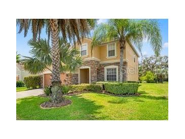 Two-story home featuring stone accents, well-maintained landscaping, and palm trees at 13830 Trull Way, Hudson, FL 34669