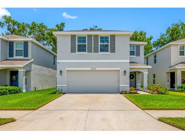 Charming home featuring a two-car garage, beautiful landscaping, and a welcoming front porch at 36652 N Spanish Rose Dr, Dade City, FL 33525
