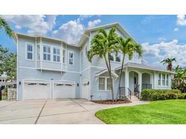 Charming light blue two-story home with a two-car garage, porch, and lush landscaping at 650 Geneva Pl, Tampa, FL 33606