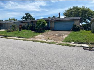 Quaint single-story home with a front lawn and an attached garage at 9510 Mark Twain Ln, Port Richey, FL 34668