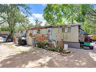 Exterior view of an older mobile home featuring a yard, trees and aged siding at 10044 Oana St, New Port Richey, FL 34654