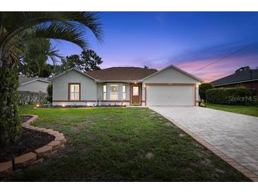 Charming single-story home features a well-manicured lawn, brick-lined driveway, and attached two-car garage at 11251 Pickford St, Spring Hill, FL 34609