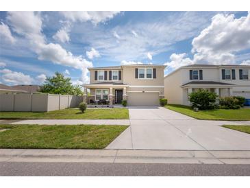 Two-story home featuring front porch seating and a two-car garage at 3052 Living Coral Dr, Odessa, FL 33556