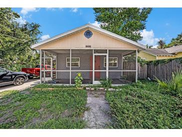 Charming single-story home featuring a screened porch, brick facade, and lovely landscaping at 8606 N 9Th St, Tampa, FL 33604