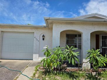 Charming home featuring a one-car garage, front yard landscaping, and an arched entryway with a security screen at 9505 Marlinton Ln, Port Richey, FL 34668
