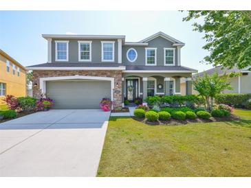 Charming two-story home features a manicured front yard, stone accents, and a two-car garage at 11044 Spring Point Cir, Riverview, FL 33579