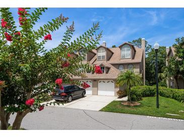 Charming townhouse with a two-car garage and inviting curb appeal, enhanced by flowering trees and lush landscaping at 2804 Countryside Blvd # 4, Clearwater, FL 33761