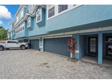 Charming condo exterior featuring blue paint, grey garage doors, and well maintained landscaping at 3111 W De Leon St # 9, Tampa, FL 33609