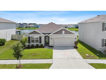 Charming single-story home with a well-maintained lawn, two-car garage, and serene lake views at 33369 Hamilton Hill Ln, Wesley Chapel, FL 33545