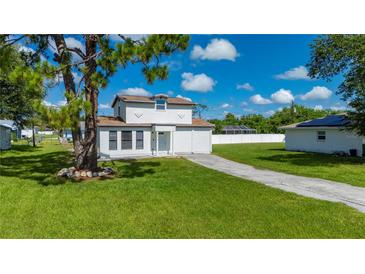 Charming two-story home with a well-manicured lawn, long driveway, and white picket fence at 3513 Syracuse St, Port Charlotte, FL 33952