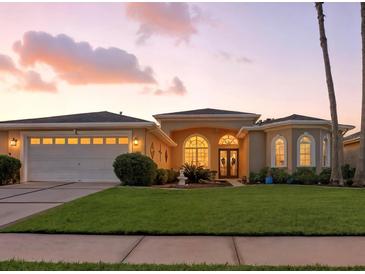 Charming single-story home with a well-manicured lawn, beautiful landscaping, and arched windows at sunset at 4428 Gevalia Dr, Brooksville, FL 34604