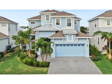 Charming three-story home features a light blue exterior, attached two car garage and beautiful landscaping at 5307 Wishing Arch Dr, Apollo Beach, FL 33572