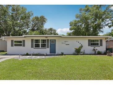 Charming single-story home featuring a well-maintained lawn and a blue front door at 1438 Poinciana Dr, Clearwater, FL 33764