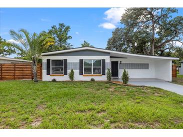 Charming single-story home with well-manicured lawn, palm tree, and attractive gray and white exterior at 4020 N Falkenburg Rd, Tampa, FL 33610