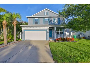 Charming two-story home featuring a two-car garage, inviting front porch, and well-manicured lawn at 7703 S West Shore Blvd, Tampa, FL 33616