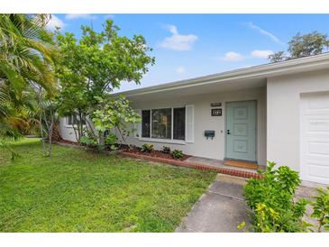 Charming single-story home featuring a quaint, light-blue front door and lush, mature landscaping at 1084 39Th Ne Ave, St Petersburg, FL 33703
