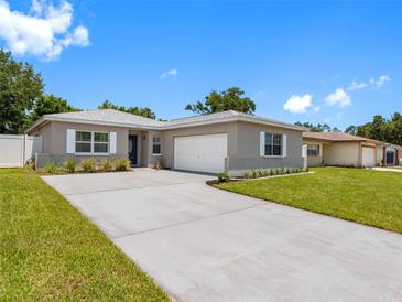 Charming single-story home with a well-manicured lawn and a long driveway leading to an attached garage at 1675 E Grovehill Rd, Palm Harbor, FL 34683