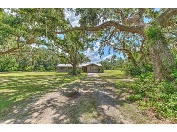 Charming single-story home with a metal roof, nestled under mature oak trees and a large front yard at 2610 Crestview Rd, Wimauma, FL 33598
