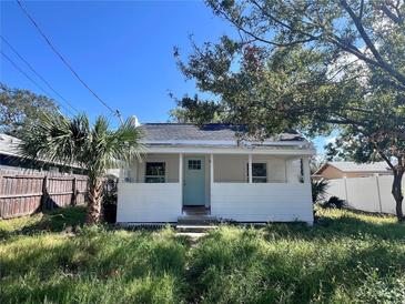 Charming white home featuring a quaint porch and a light blue front door, surrounded by lush greenery at 368 6Th Nw St, Largo, FL 33770