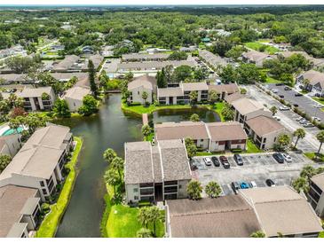 Aerial view of the community, showing lush landscaping, serene pond, and well-maintained buildings and parking areas at 3836 N Lake Dr # 121, Tampa, FL 33614