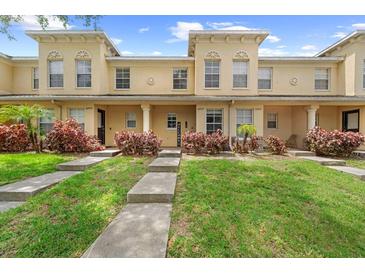 Charming townhome featuring a well-manicured lawn, walkway, and inviting facade under a clear blue sky at 10947 Brickside Ct, Riverview, FL 33579