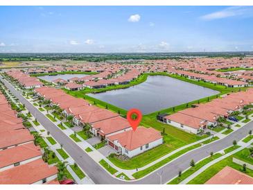 Stunning aerial view of a lakeside community with manicured lawns and red-tiled roofs on a bright day at 17415 Holly Well Ave, Wimauma, FL 33598