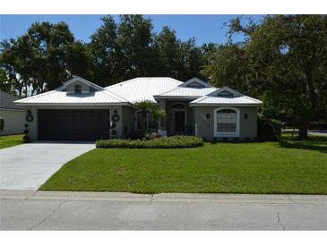 Charming single-story home featuring a metal roof, well-manicured lawn, and two-car garage at 3212 Stevenson St, Plant City, FL 33566