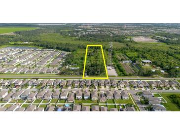 Aerial view of land for sale between neighborhood and wooded area with a yellow rectangular border at 11109 Sumner Rd, Wimauma, FL 33598