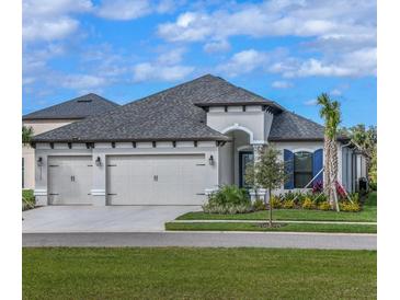 New home with a three-car garage, lush landscaping, and beautiful lawn at 11324 Striped Bass Ct, New Port Richey, FL 34654
