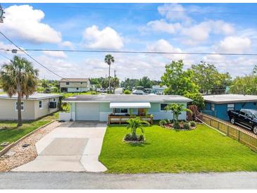Charming single-story home with lush lawn, pretty landscaping, and a covered front porch at 13316 Carol Dr, Hudson, FL 34667
