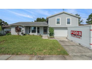 Charming two-story home with a well-maintained lawn and a brick accent wall, featuring a PODS moving container in the driveway at 15612 Farnsworth Ln, Tampa, FL 33624