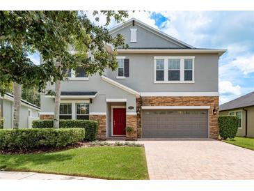 Charming two-story home with stone accents, a red door, and a well-manicured front yard at 19309 Prairie Tree Pl, Tampa, FL 33647
