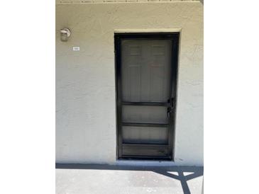 Image of the front door to unit 1512 with a black screen door on a stucco wall at 2625 State Road 590 # 1512, Clearwater, FL 33759