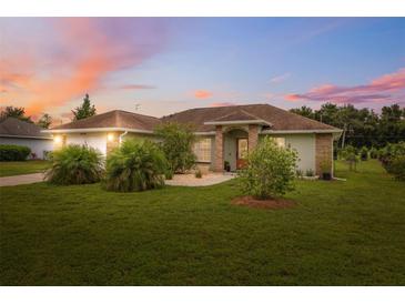 Charming single-story home with a well-manicured lawn and mature landscaping under a lovely sunset at 40449 Trotter Ln, Dade City, FL 33525