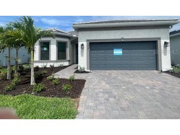 Beautiful one-story home featuring a two-car garage, stone driveway, green lawn and fresh, tropical landscaping at 4947 Ribbon Rock Cv, Lakewood Ranch, FL 34211
