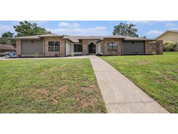 Inviting single-story home featuring a well-manicured lawn, brick accents, and a pathway leading to the front door at 513 Sportsman Park Dr, Seffner, FL 33584