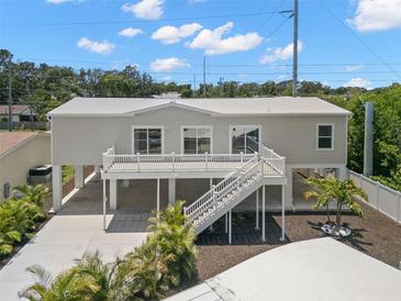 Beautiful elevated home featuring a white exterior, large deck, and well-manicured landscaping at 6924 Americana Ne Dr # 167, St Petersburg, FL 33702