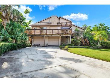 Two-story home with a large deck, two-car garage, and a spacious driveway surrounded by lush greenery at 101 Carlyle Dr, Palm Harbor, FL 34683