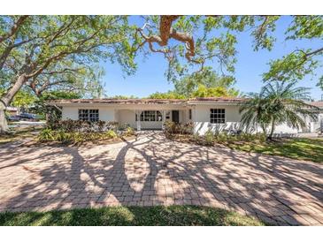 Charming single-story home with a red tile roof and a brick paved driveway lined with mature trees at 1100 Snell Isle Ne Blvd, St Petersburg, FL 33704