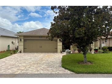 Charming home featuring a two-car garage with a brick-paved driveway and lush lawn at 29524 Waggle Dr, San Antonio, FL 33576