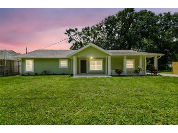 Charming, updated single-story home features a cozy front porch and lush green lawn at 7308 Avonwood St, Tampa, FL 33625